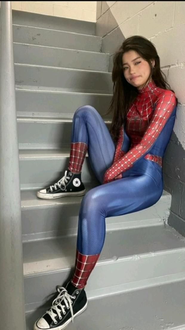 a woman in blue and red spider suit sitting on stairs