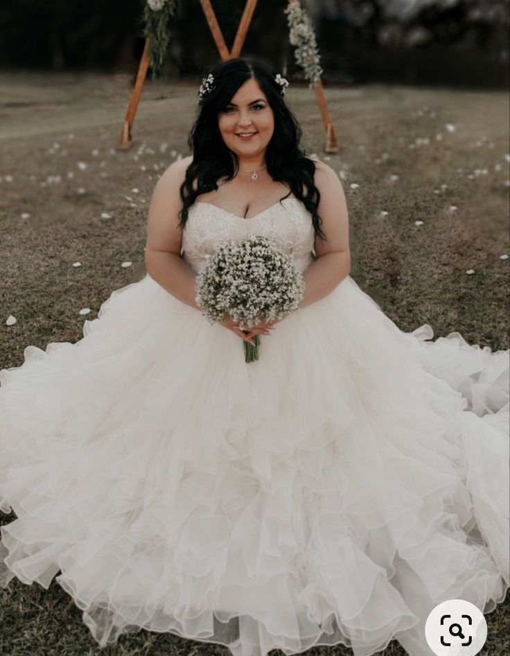 a woman in a wedding dress sitting on the ground