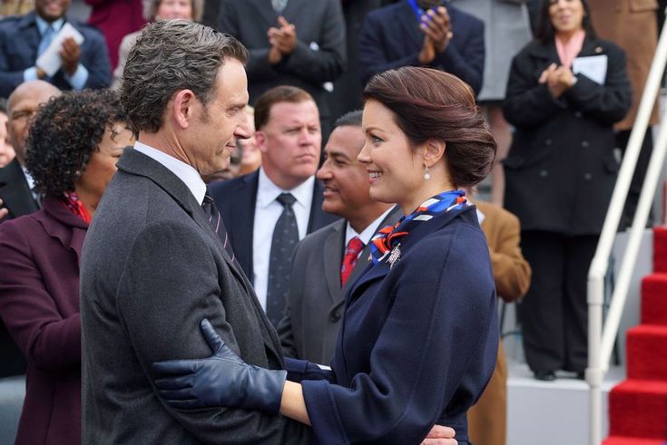 a man and woman are shaking hands in front of a group of people on steps