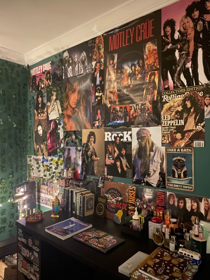 a room with many posters on the wall and various items on the desk in front of it