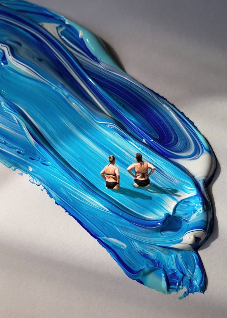 two people are swimming in the water with blue and white swirls on it's surface