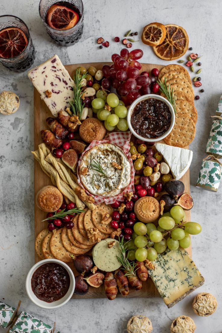 a cheese board with crackers, grapes, crackers, and other snacks on it