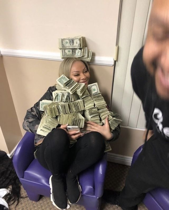 a woman sitting in a chair with stacks of money on her head and another person standing next to her