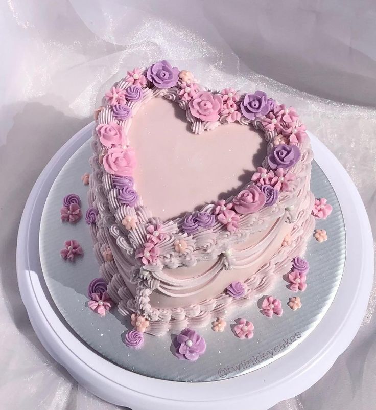 a heart shaped cake sitting on top of a white platter covered in frosting