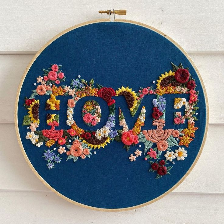 the word love is made up of flowers on a blue hoop hanging from a wall