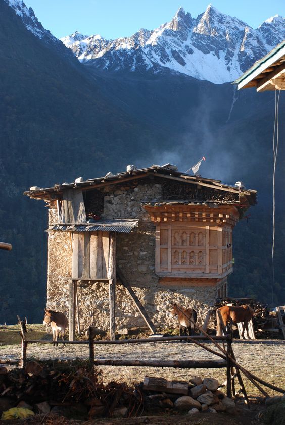 an old stone house with mountains in the background