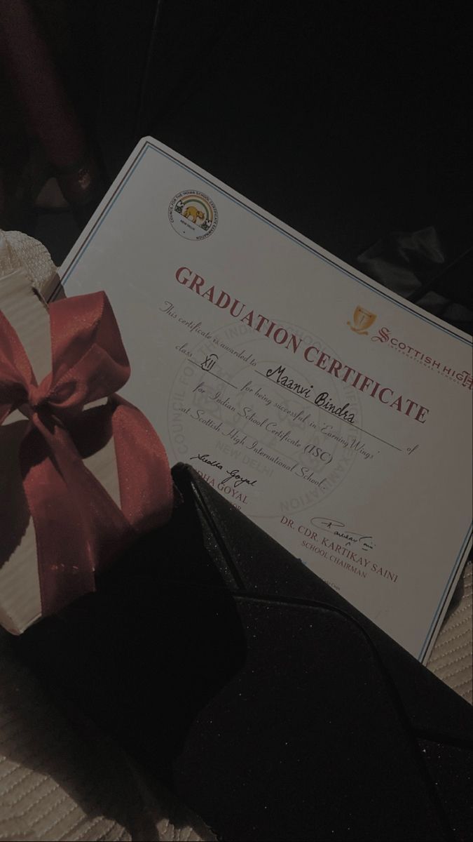 a diploma certificate with a pink ribbon on top of it next to a black purse