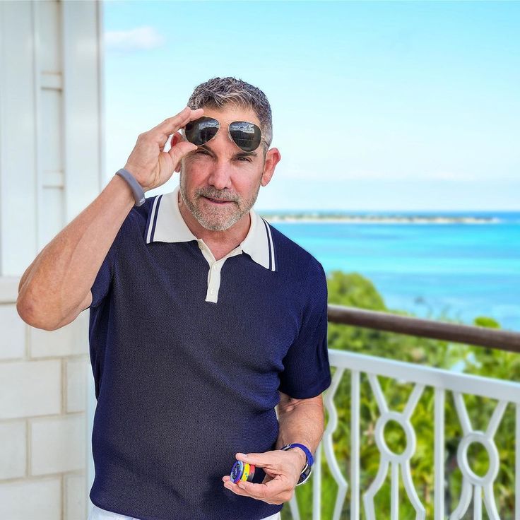 a man with sunglasses on his head looking into the distance while standing in front of a balcony