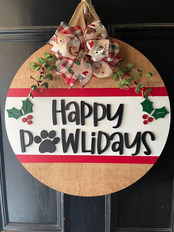 a wooden sign that says happy holidays hanging on a door with a bow and dog's paw