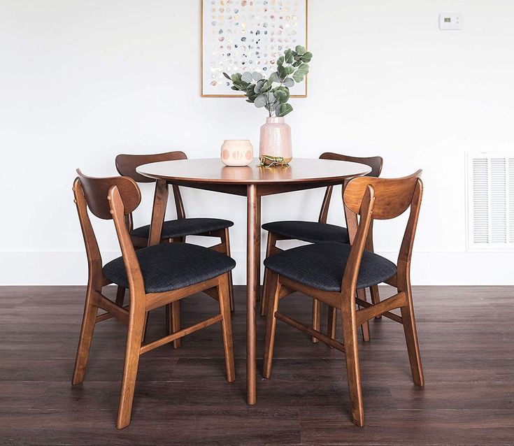 a table with chairs and a vase on top of it in front of a white wall