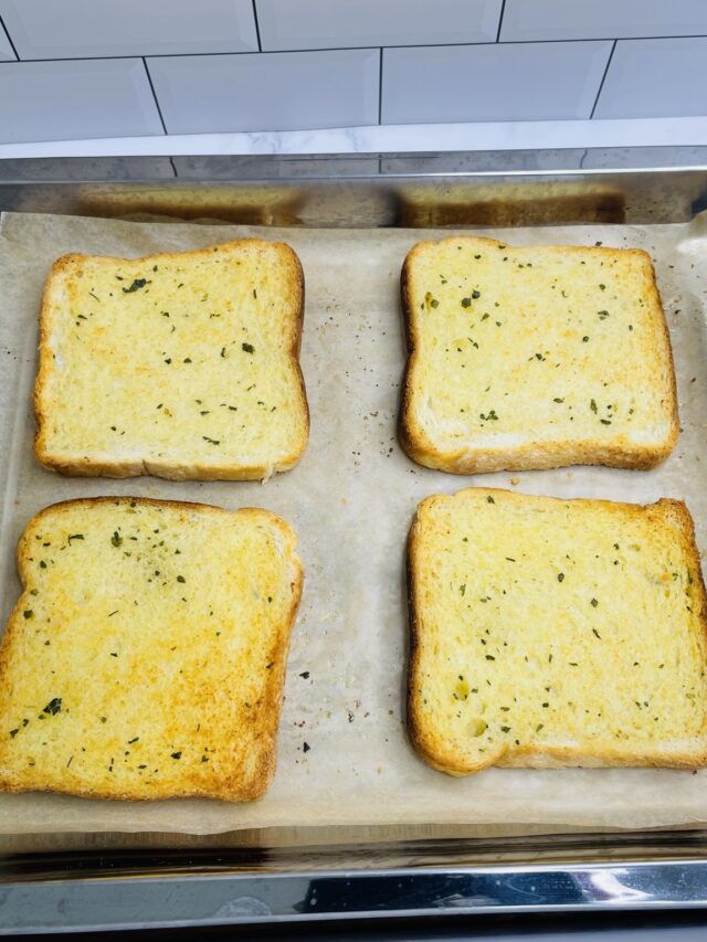 four pieces of bread with cheese and herbs on them sitting in a baking pan, ready to go into the oven