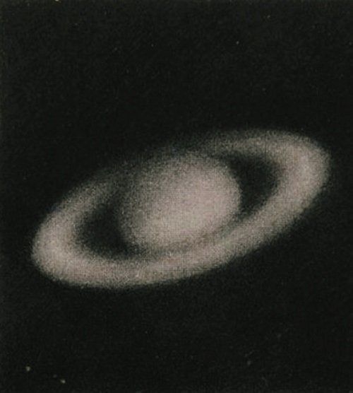 a black and white photo of a ringed object in the night sky, taken from below