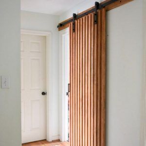 an open sliding door with wooden slats on the side and wood flooring in front