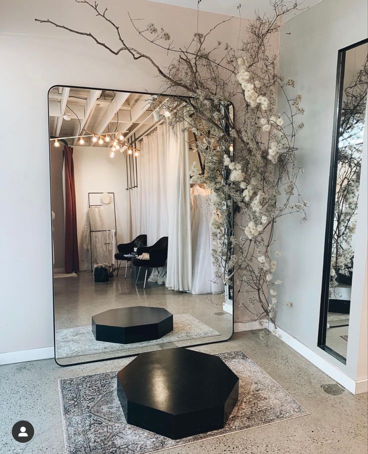 a large mirror sitting on top of a floor next to a black table and chair