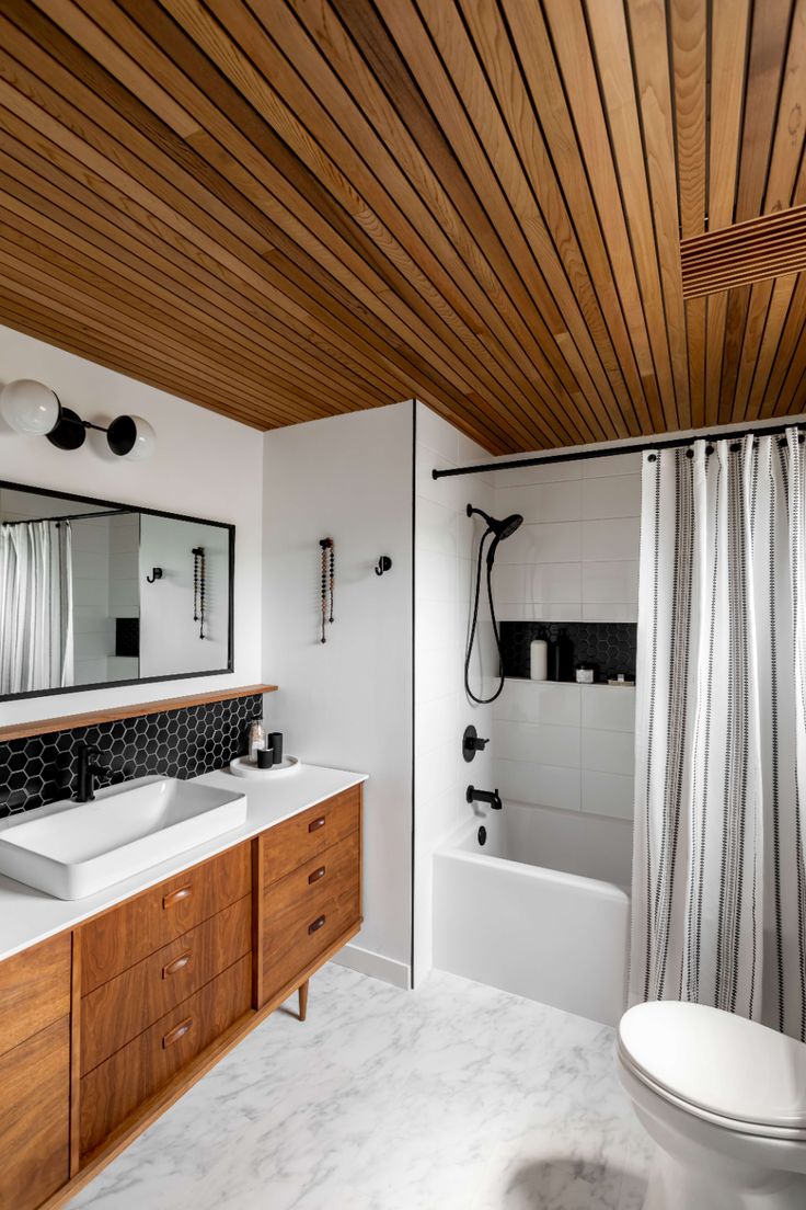 a bathroom with wood ceiling and white counter tops, along with a wooden shower curtain