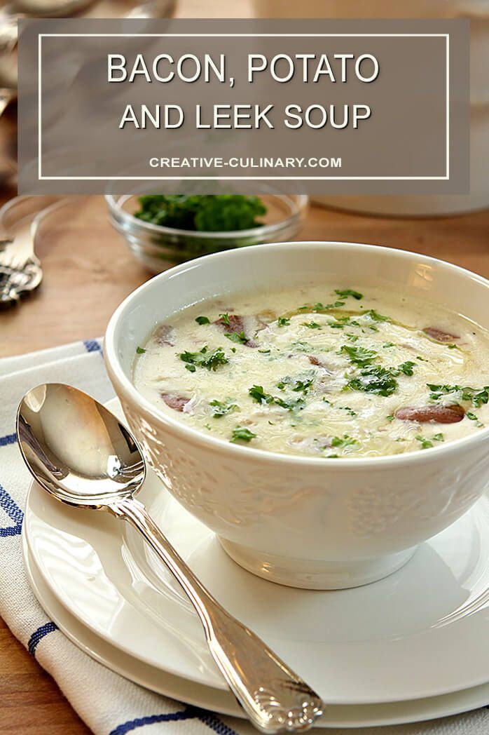 a bowl of soup on a white plate with silver spoons next to another bowl