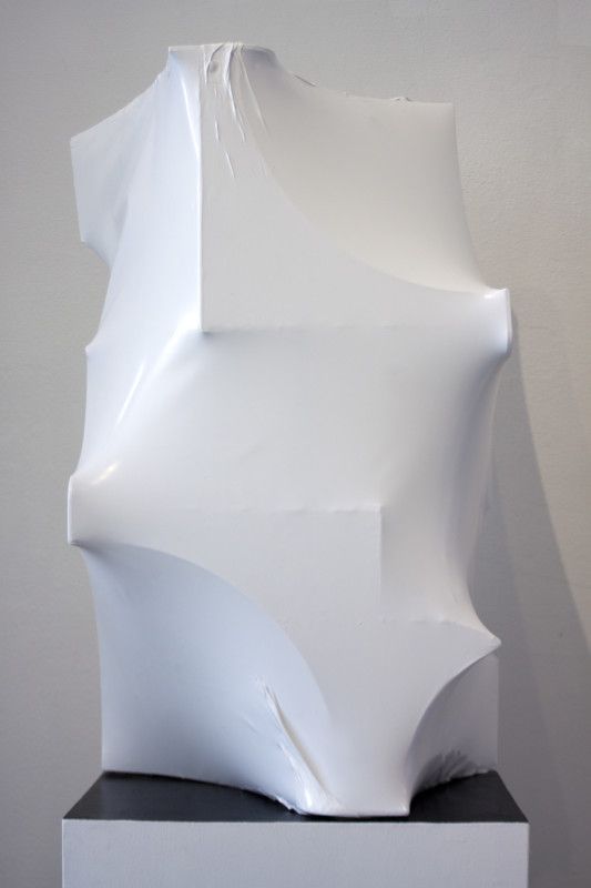 a white sculpture sitting on top of a black pedestal in front of a gray wall