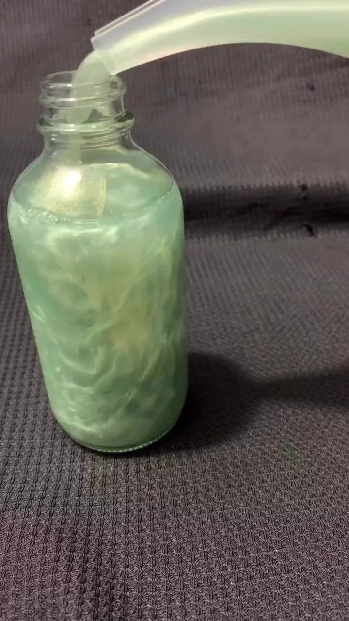 a glass jar filled with green liquid sitting on top of a gray carpeted floor