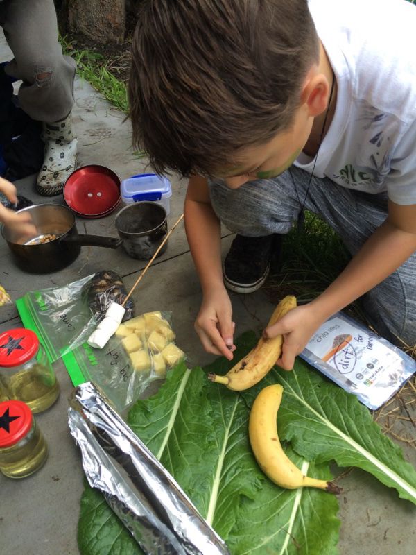 a young boy cutting bananas on top of a green leafy plant next to other food items