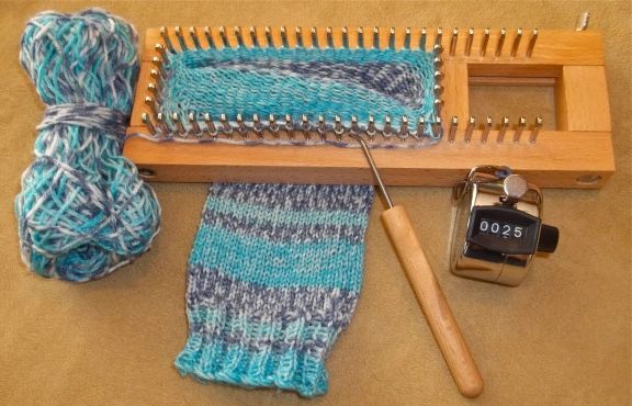 a pair of knitting needles and yarn next to a sewing needle with a wooden spool