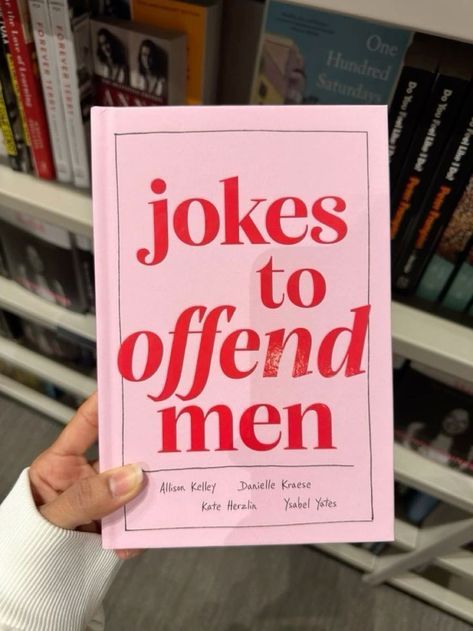 a person holding up a pink book with the title jokes to offend men written on it