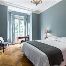 a bedroom with blue walls and hardwood floors, white bedding, and a chandelier hanging from the ceiling