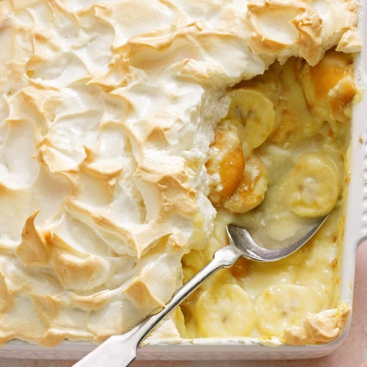 a person holding a spoon in a casserole dish with bananas and whipped cream