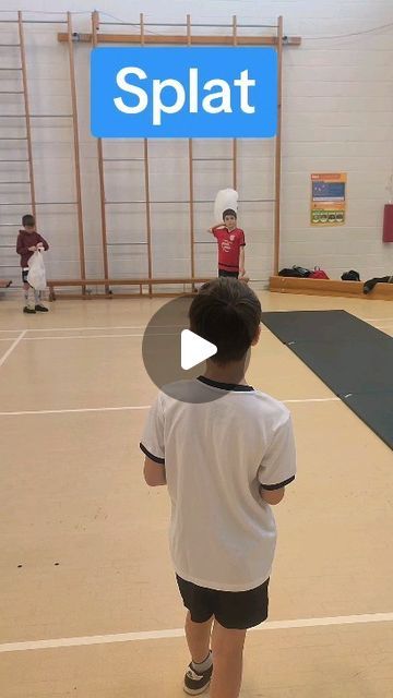 a young boy is playing with a frisbee in an indoor gym while others watch