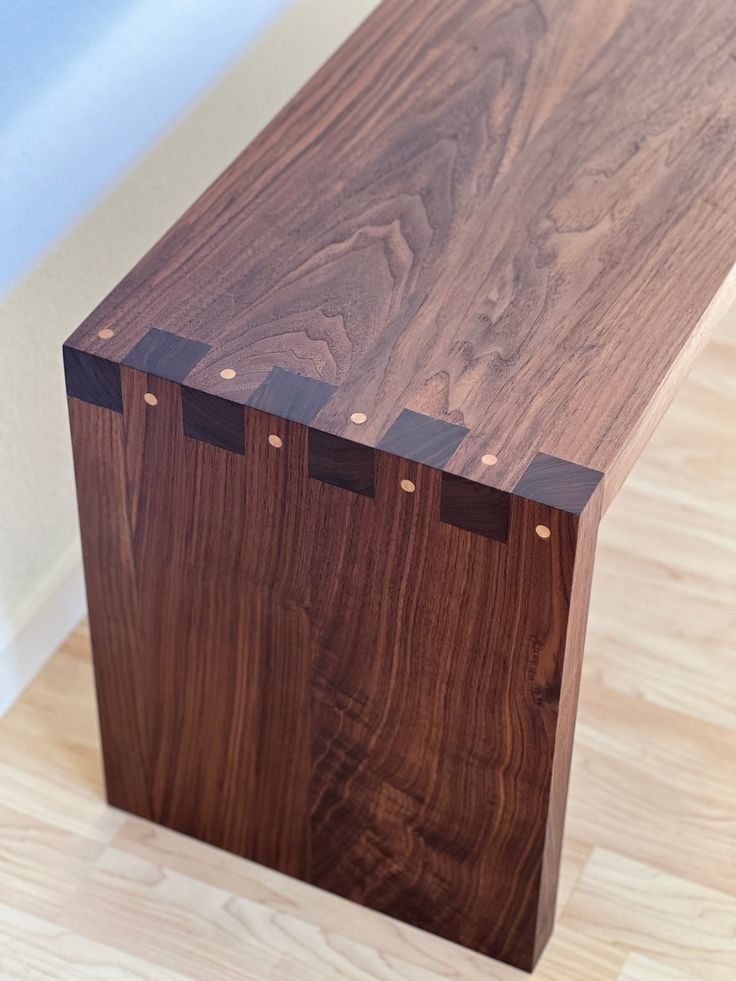 a wooden bench sitting on top of a hard wood floor next to a white wall