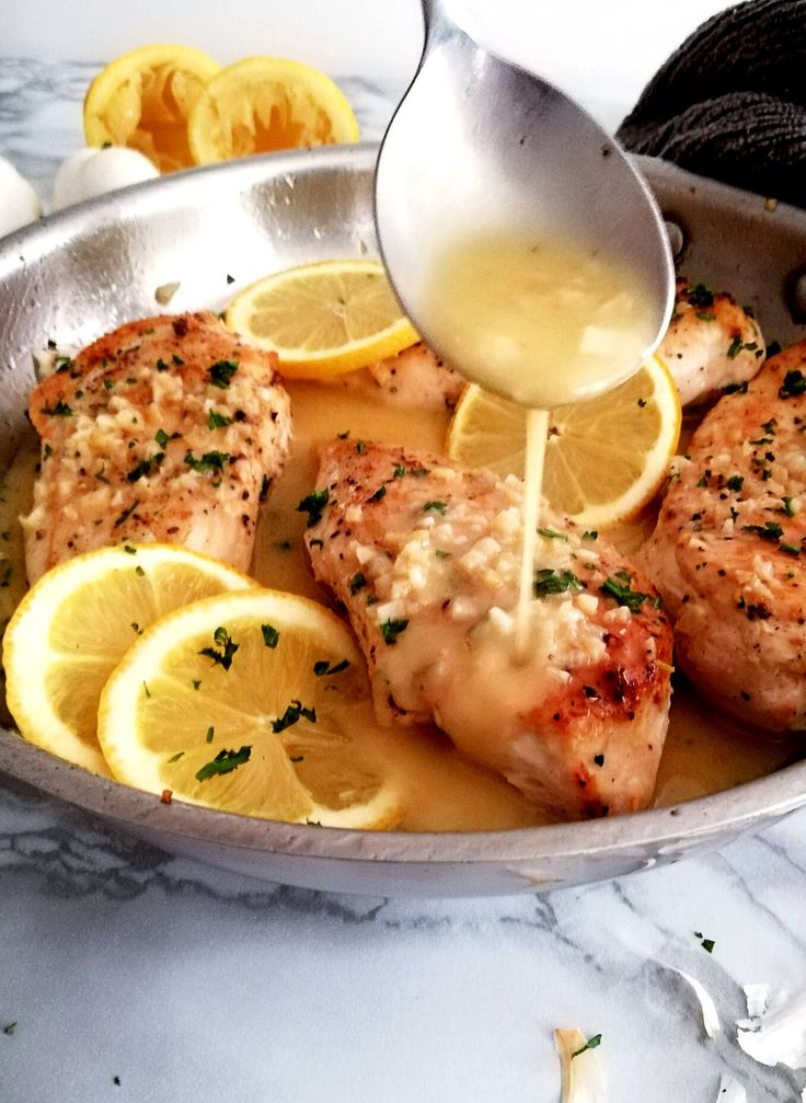 someone is pouring sauce on some chicken with lemons