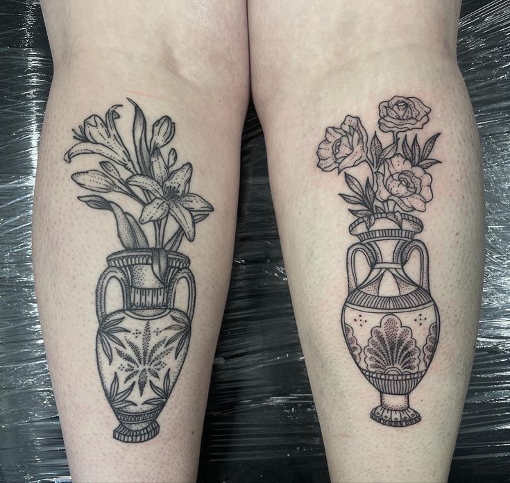 two black and white vases with flowers on their legs