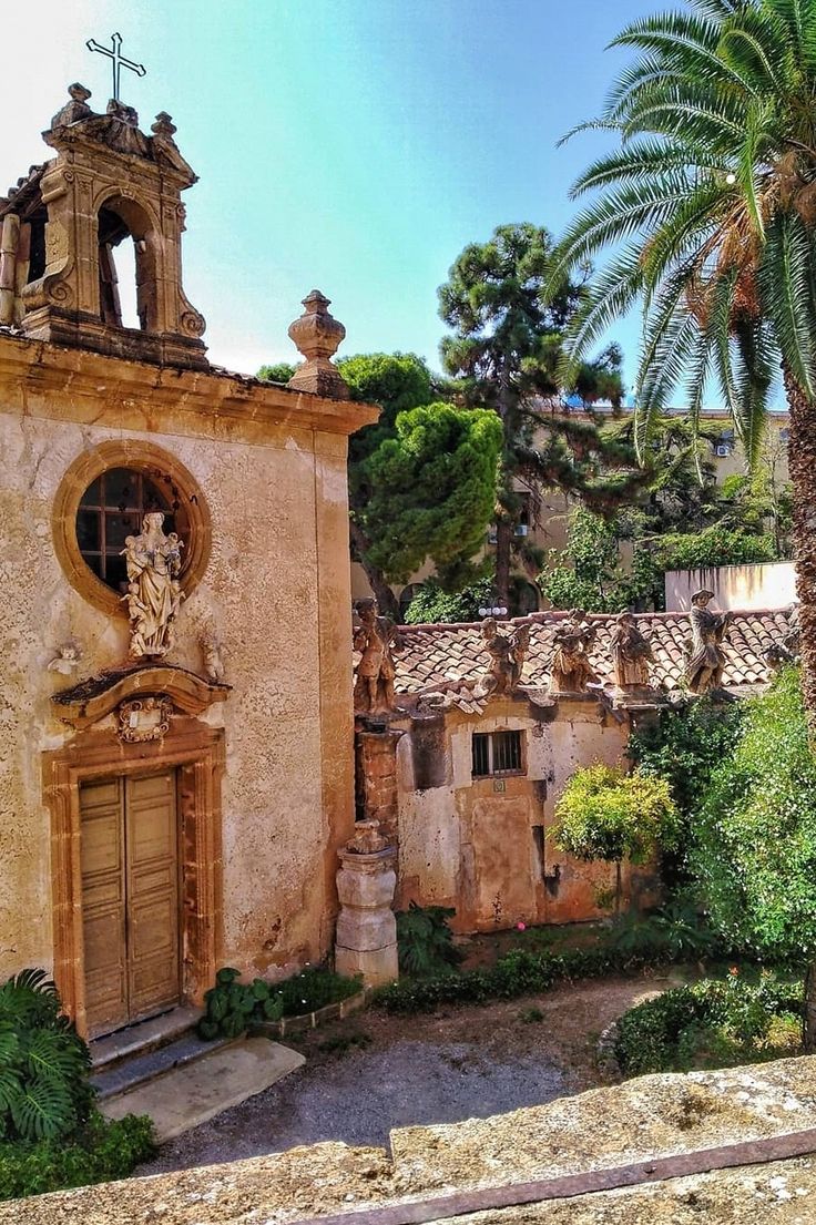 an old building with a clock on the side and palm trees in front of it