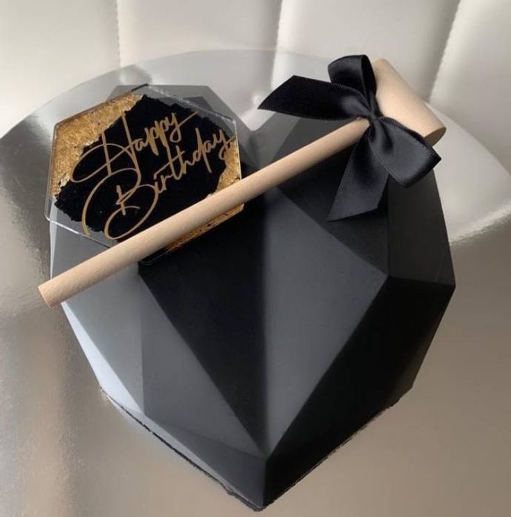 a black and gold birthday cake with a wooden stick