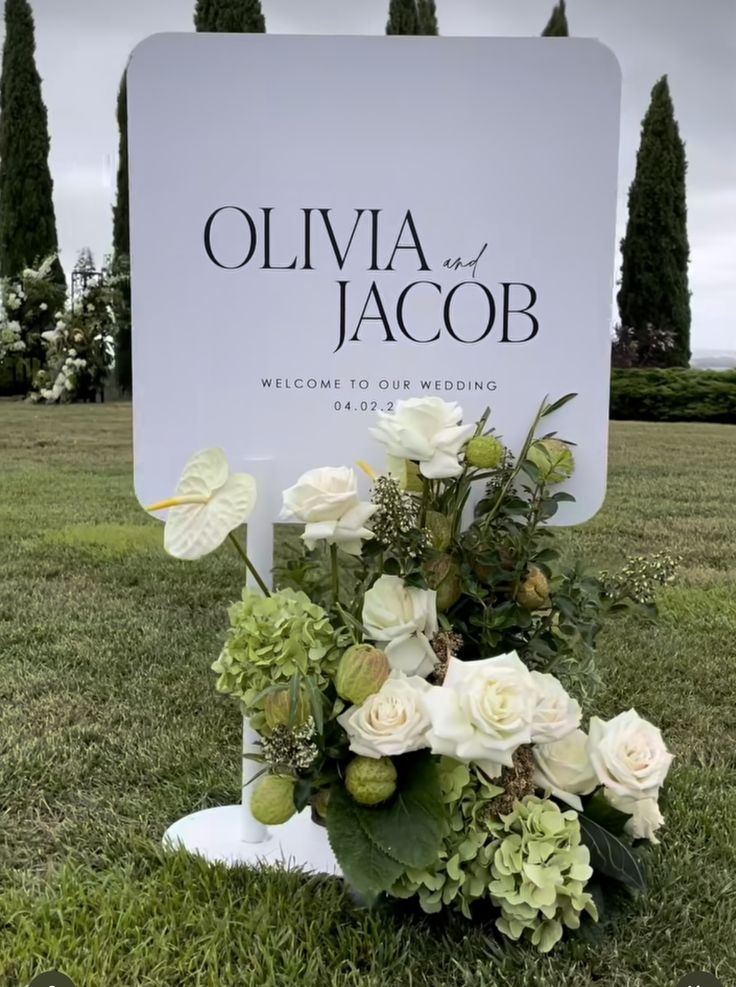 a bouquet of flowers sitting in the grass near a sign that says oliva and jacob