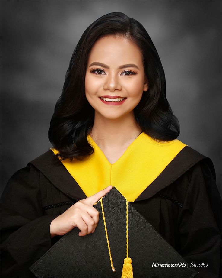 a woman wearing a graduation gown and holding a black cap with a yellow tassel