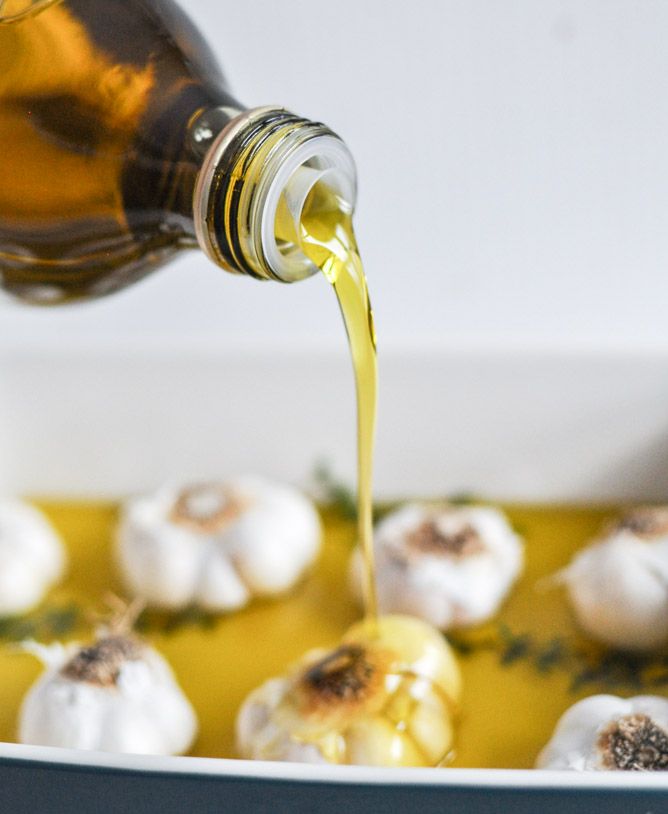 a bottle pouring oil on some food in a pan