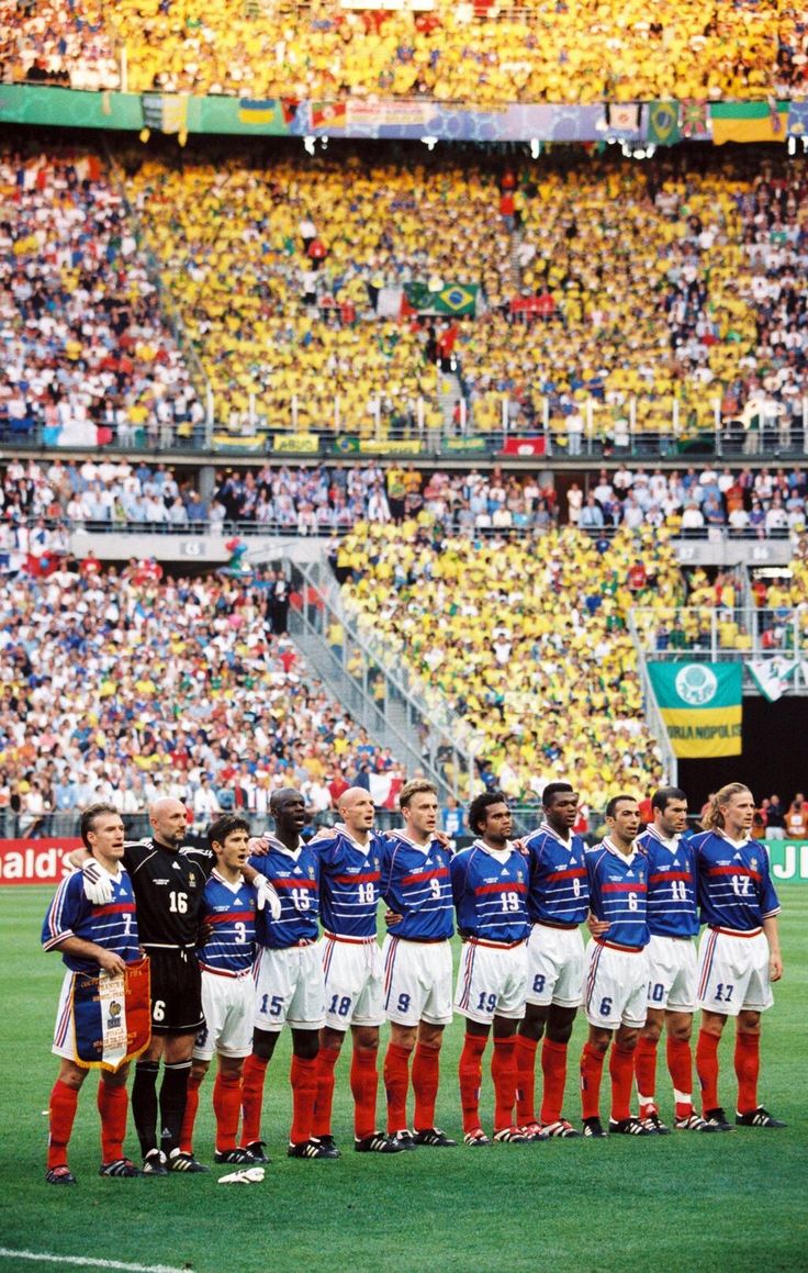 a group of soccer players standing on top of a field next to each other in front of a crowd