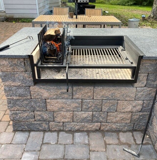 an outdoor grill is set up on a brick patio