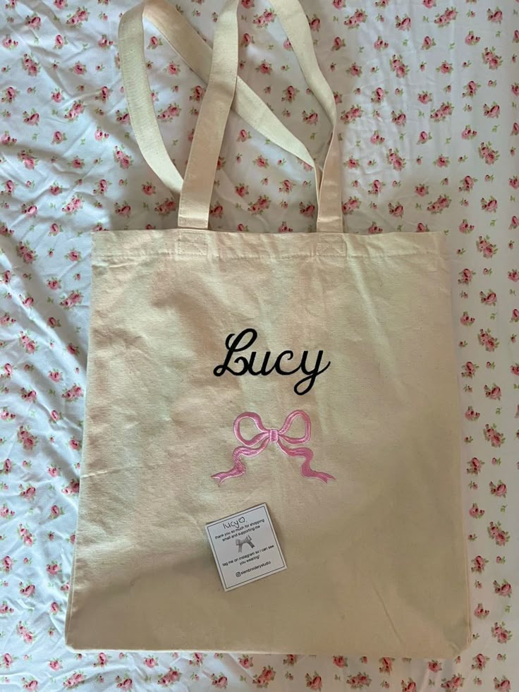 a white bag with a pink bow on it and the word bucy written in black