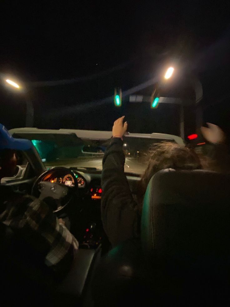 two people sitting in the driver's seat of a car at night