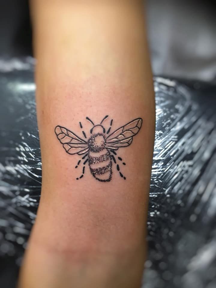 a small bee tattoo on the leg