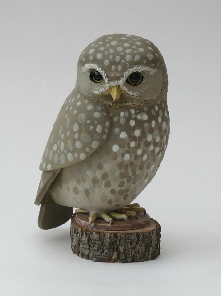 an owl figurine sitting on top of a piece of wood with white dots