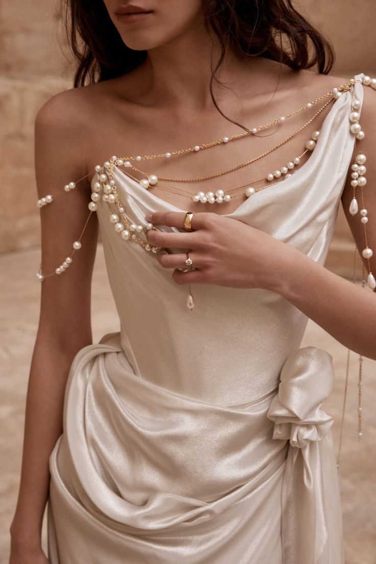 a woman in a white dress with pearls on her shoulder