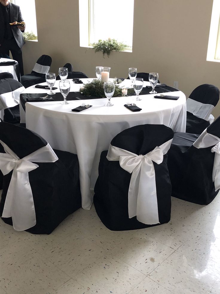 black and white chairs with bows on them are set up for a formal function at the reception