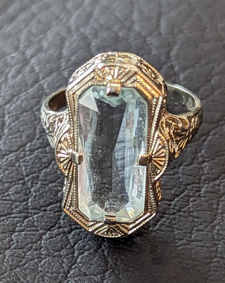 Antique 1920s era Art Deco Aquamarine ring. Aquamarine is emerald cut and weighs 4.8 carats. Stone is prong set in an ornate 14k White Gold filigree setting with miligrain work on edges. Aquamarine is March's birthstone. The ring is fully hallmarked and will arrive gift boxed. MARKS 14k. CONDITION In very good to excellent condition with light wear. Please use all pictures as part of item's description. SIZE 5 1/2, ring could be resized by any good jeweler. MATERIALS Aquamarine, 14k White Gold Vintage 14k Stamped Sapphire Ring For Formal Occasions, Art Deco 14k Gold Emerald Ring, Vintage White Gold Emerald Jewelry, Collectible Art Deco Emerald Ring, Art Deco Emerald Ring With 17 Jewels For Anniversary, Art Deco Emerald Ring With 17 Jewels, Art Deco Rectangular Emerald Ring For Anniversary, Art Deco Emerald Ring In Baguette Cut White Gold, Art Deco Sapphire Ring With Baguette Cut