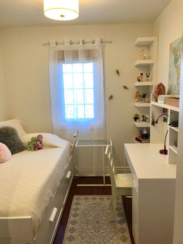 a bedroom with a bed, desk and shelves on the wall in front of a window