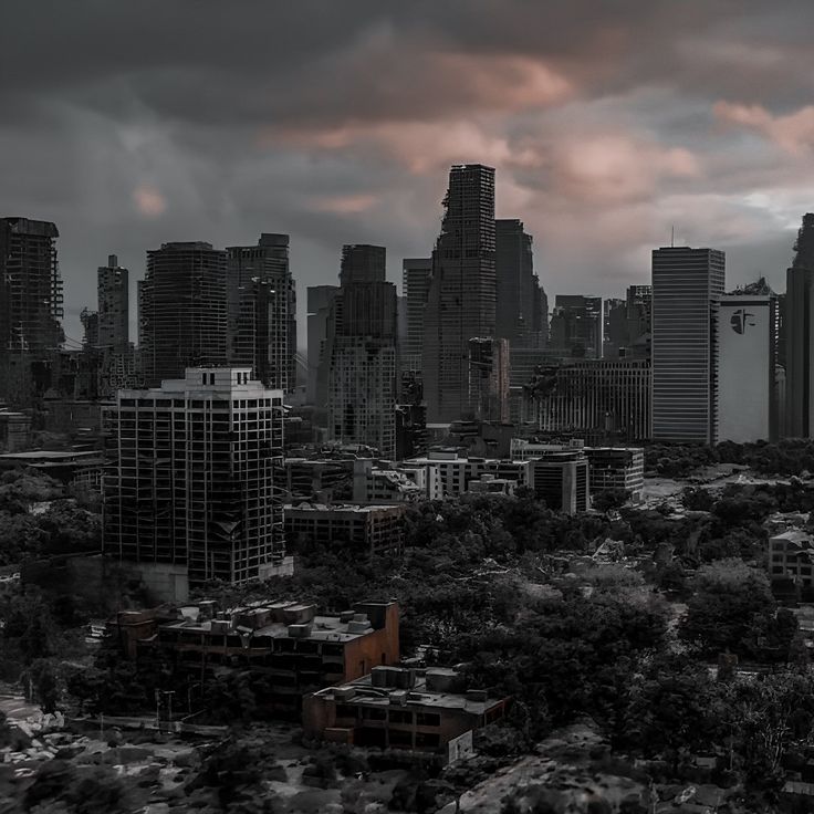 an aerial view of a city with tall buildings in the foreground and dark clouds in the background