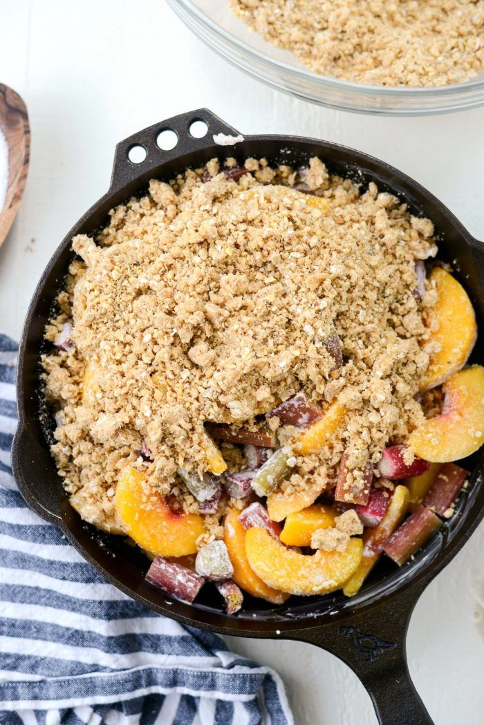 a skillet filled with fruit and crumbs on top of a table