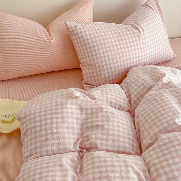 a bed with pink gingham comforter and two pillows on top of it