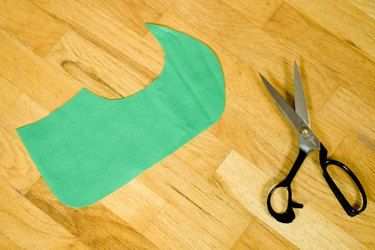 a pair of scissors sitting on top of a wooden floor next to a piece of green paper